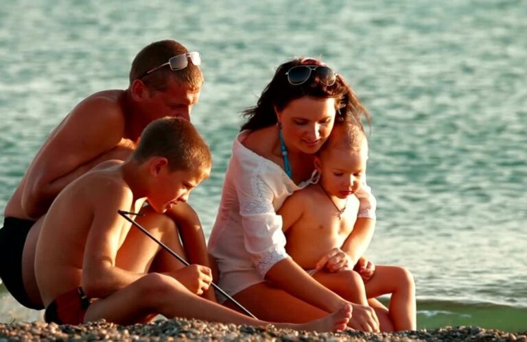 Porodica sedi na plaži sa decom