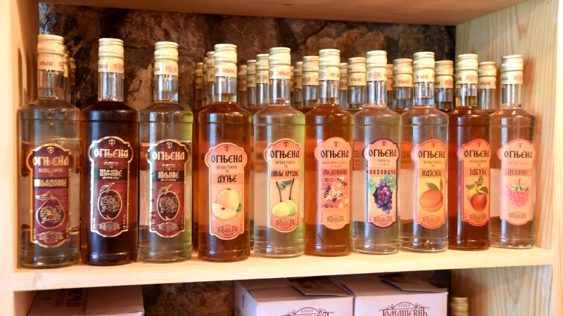Flaše Ognjena rakije poređane na drvenoj polic