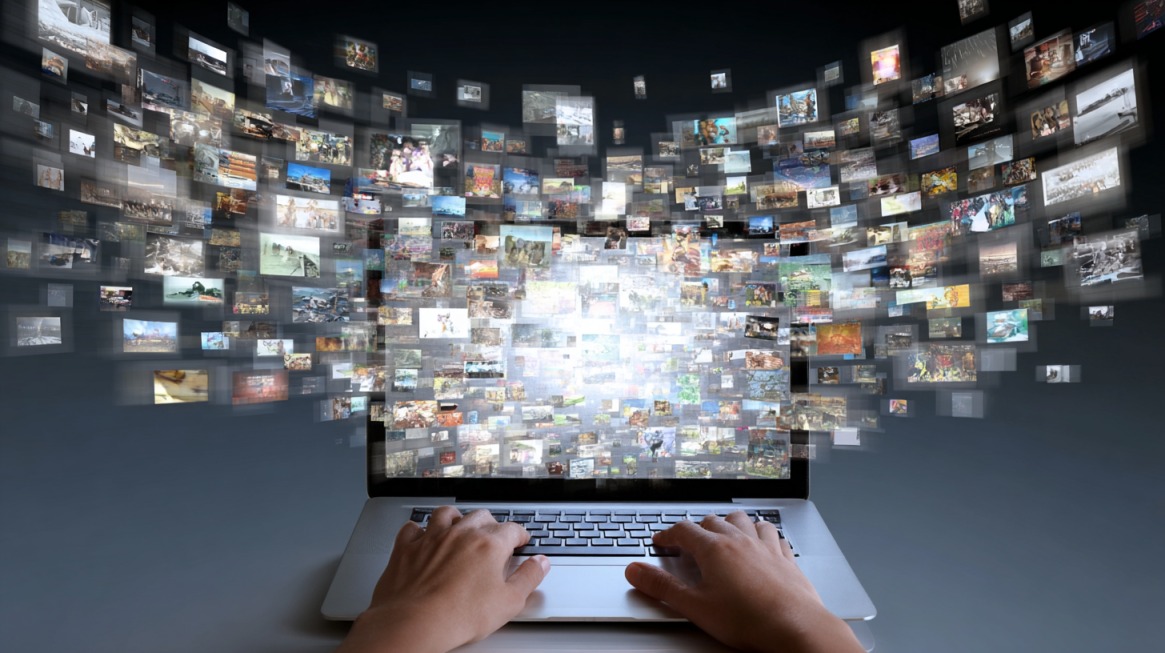 Ruke na laptopu dok se iz ekrana širi mnoštvo digitalnih slika koje simbolizuju ogroman broj sajtova na internetu