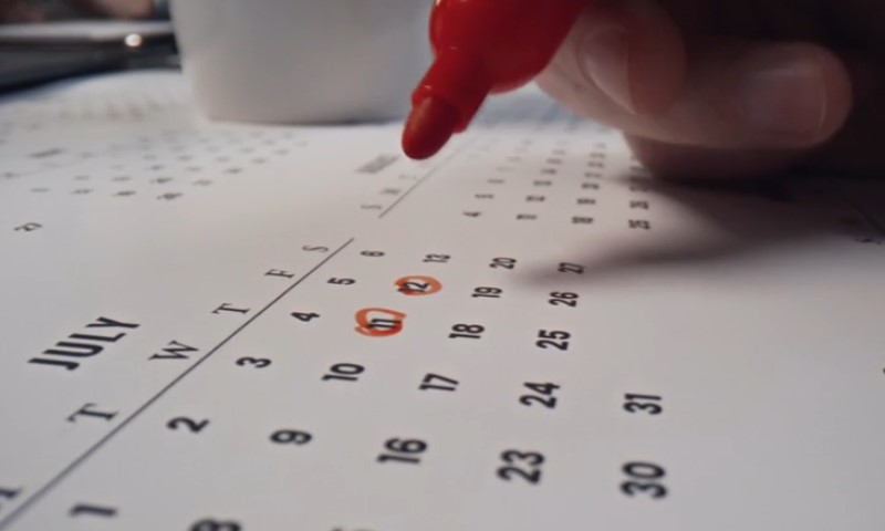 Osoba crvenim markerom zaokružuje dane na kalendaru