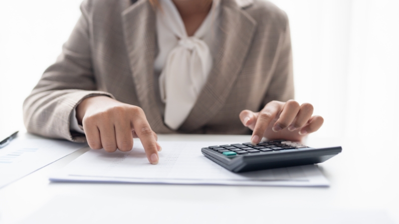 Žena proverava finansijske podatke i računa troškove na digitronu kao deo kontrole novčanog toka