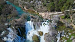 Pogled iz vazduha na vodopad Kravice, reku Trebižat i okolnu prirodu.